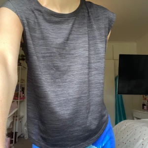 Träningströja - Sportig svart topp från SOC i storlek XS. Toppen har ett diskret melerat mönster, rund halsringning och ärmlös design med breda axlar. Tillverkad i ett lätt och snabbtorkande syntetmaterial som andas, perfekt för träning och aktiva dagar🙌🏻Tunn och skön, bra till sommaren😻Använd någon gång så i toppen skick!