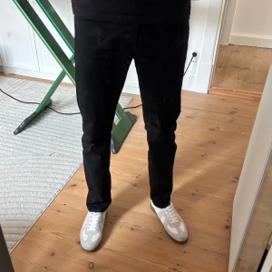 Svarta jeans från Lee, straight fit - Säljer ett par svarta jeans från Lee med klassisk femficksdesign och diskret Lee-logga på bakfickan. Jeansen har rak passform och normal midja, tillverkade i mjukt jeanstyg som sitter snyggt på benen. Perfekta till sneakers och t-shirt.