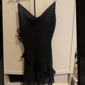 Svart glittrig kortklänning med volang - Supersöt svart kortklänning med tunna axelband och glitter