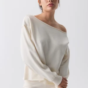 Offshoulder vit tröja i bomull - Snygg offshoulder tröja i mjuk vit bomull med avslappnad passform och långa ärmar. Perfekt för dig som gillar en chill och trendig stil. Tröjan har bred halsringning som visar axlarna och ribbade muddar vid ärmsluten.