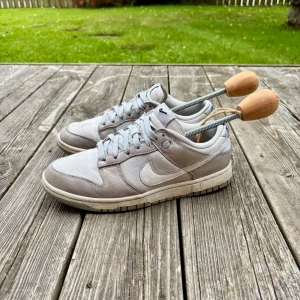 Gråa Nike dunk low - Säljer mina feta gråa dunks! Skicket är riktigt bra 9/10 förutom lite crease linjer längst fram på skon som syns på bilderna. Strl är 39, hör av er vid frågor!