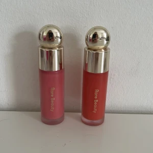 Rare Beauty flytande rouge duo - Två flytande rouge från Rare Beauty i nyanserna Happy (rosa) och Joy (korall). Kommer i snygga frostat glasflaskor med guldiga klotformade lock och mjuk applikator. Perfekt för att ge kinderna en fräsch och naturlig färg.