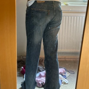Levi's 501 raka jeans blå denim - Klassiska Levi's 501 jeans i blå denim med raka ben och normal passform. Jeansen har fem fickor, knappgylf och den ikoniska röda Levi's-taggen bak. Snyggt slitna detaljer och vintagekänsla, perfekta för en avslappnad look. W32/ L34 dom. Är för långa på mig som är 163 cm 