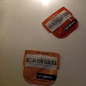 Sol de Janeiro Bum Bum & Bright Cream - Två ikoniska kroppskrämer från Sol de Janeiro: Brazilian Bum Bum Cream i gul förpackning och Bom Dia Bright Cream i orange/röd förpackning. Perfekta för att återfukta och ge glow till huden. Smidiga reseförpackningar i plast.