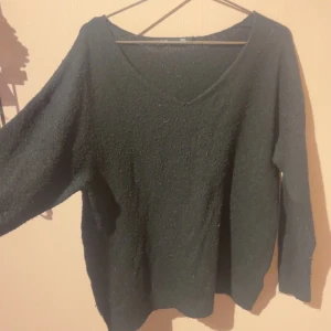 Svart stickad tröja från 157 - Mysig svart stickad tröja från 157 med v-ringad hals och lång ärm. Perfekt för lager-på-lager och chill dagar. Enkel och stilren design som funkar till det mesta. Säljes i storlek S.