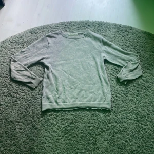 Ljusgrå stickad tröja från H&M -  Fick hål i båda arm hålorna men är laggade. En basic ljusgrå stickad tröja från H&M i storlek 134/140. Tröjan har rund halsringning, ribbade muddar och är långärmad. Perfekt för lager-på-lager och funkar året runt. Enkel och stilren design som passar till det mesta.