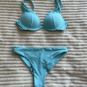 Ljusblå bikini med vadderad topp - Snygg ljusblå bikini med vadderad bygel-bh och justerbara axelband. Bh:n är pushup. Underdelen har klassisk midja och enkel design. Toppen stängs med spänne i ryggen. Perfekt för strand eller poolhäng i sommar.