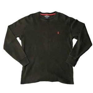 Ralph lauren tröja  - Säljer en stilren svart långärmad tröja från Polo Ralph Lauren med röd logga på bröstet. Tröjan har en klassisk rund halsringning och är perfekt för en avslappnad look. Passar bra till jeans eller chinos.