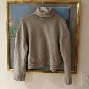 Beige polotröja från H&M - Mysig beige polotröja från H&M med ribbade muddar och hög krage!
