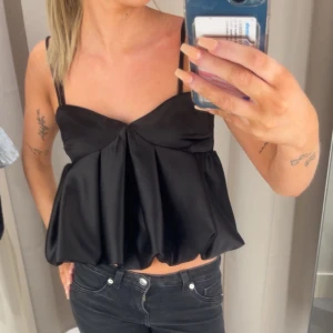 Svart satinlinnetopp - Supersnygg svart satin topp med fluffig del nertill 