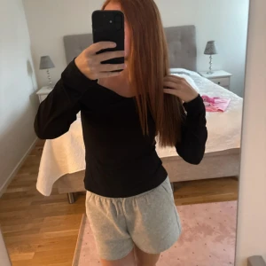 Svart offshoulder långärmad topp - Säljer en svart långärmad topp med offshoulder-design och snygg omlott-detalj över bröstet. Tröjan har en tight passform och är perfekt för dig som gillar stilrena och trendiga plagg. Materialet känns mjukt och följsamt mot kroppen.