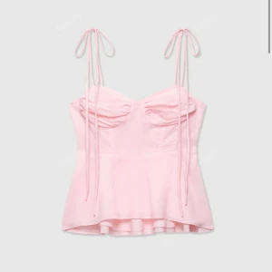 Ljusrosa linnetopp med knytband - Supersöt ljusrosa linnetopp med tunna axelband som knyts upptill. Toppen har en lätt utsvängd nederdel och rynkade kupor framtill för en feminin look. Perfekt för varma dagar och ger en romantisk vibe till din outfit. Mer aprikos än rosa🩷