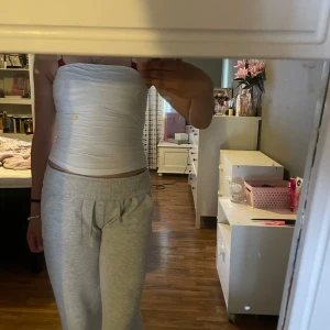 Vit tubtopp - Säljer en enkel vit tubtopp med slät yta och ganska tajt material. Toppen är ärmlös och axelbandslös, perfekt för varma dagar eller som lager under andra plagg. Snygg och basic stil som passar till det mesta.