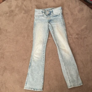 Ljusblå bootcut jeans med slitningar - Säljer ett par ljusblå jeans med bootcut-modell och snygga slitningar på låren. Jeansen har  slitits lite  pga användning 