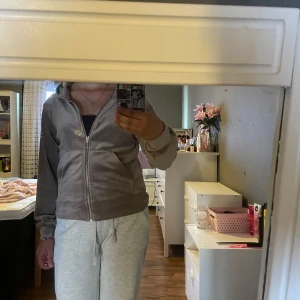 Beige kofta med dragkedja - Mjuk och skön beige kofta med huva och hel dragkedja framtill. Jackan har långa ärmar och två fickor på sidorna. Perfekt för en avslappnad och chill stil.