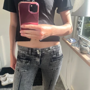bootcut jeans från Nelly - Säljer ett par grå jeans med bootcut och låg midja. Jeansen har stora fickor framtill och markerade sömmar längs benen. Snygg tvättad look och raka ben som släpper ut nertill. Perfekta för dig som gillar en chill och trendig stil.