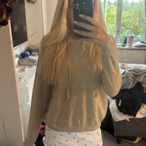 Beige hoodie med huva och snörning - Säljer en beige hoodie med huva och snörning framtill. Tröjan har långärmad passform och ribbade muddar vid ärmslut och nederkant. Perfekt för en chill och avslappnad stil. Supermjuk och enkel att matcha med det mesta. 🥰