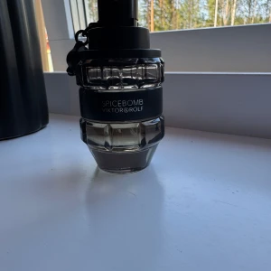 Spicebomb parfym - Spicebomb från Viktor & Rolf är en ikonisk herrparfym i en cool, granatinspirerad flaska av genomskinligt och svart glas. Doften är kryddig och maskulin, perfekt för dig som gillar intensiva och unika parfymer. Flaskan har en robust och modern design. Flaskan är ungefär halvfull. Box ingår ej