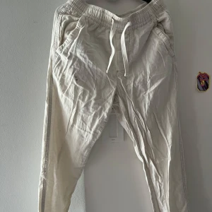 Vita mjukisbyxor från Zara med snörning - Säljer ett par vita mjukisbyxor från Zara i storlek S. Byxorna har resår och snörning i midjan, sidofickor och bakfickor. De är tillverkade i ett mjukt bomullstyg och har en avslappnad passform som är perfekt för chill dagar. Mindre fläck som lätt går att få bort! 