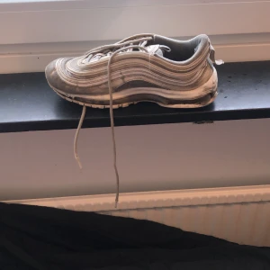 Grå Nike sneakers - Säljer ett par grå Nike sneakers med snörning och rund tå. Skorna har en stilren design med vågformade detaljer längs sidorna och en bekväm sula.