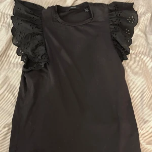  Topp med volangärmar - Säljer en svart topp från Vero Moda med volangärmar i storlek XS, helt oanvänd.