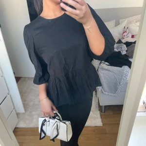 Svart blus med knyt i ryggen - Snygg svart blus med trekvartsärm och knyt i ryggen. Perfekt för en stilren look. Blusen har en lätt volangdetalj vid midjan som ger en feminin touch. Mycket bra skick säljs för 250 men pris kan diskuteras vid snabba köp! <3