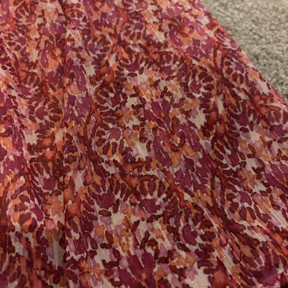 Snygg långkjol från SUD Express i en härlig mix av rosa och orange toner. Kjolen har ett blommigt mönster och är perfekt för sommarens varma dagar. Den är tillverkad i ett lätt och luftigt material som ger en skön känsla.. Hameet.