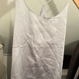 Ljusgrått linne  - Säljer en stilren ljusgrå topp med smala axelband. Perfekt för en elegant look. Linnet har en enkel design som gör den lätt att matcha med olika accessoarer. Tar emot prisförslag💗