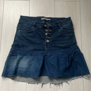 Jeanskjol med volang - Snygg jeanskjol från Zara med volangdetalj och knappar framtill. Kjolen har en klassisk blå denimfärg och praktiska fickor både fram och bak. Perfekt för en avslappnad stil med en twist. 🦋