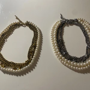 Två halsband med pärlor och kedjor - Säljer två stiliga halsband, ett med guldiga kedjor och ett med silverfärgade kedjor, båda med vita pärlor. Perfekta för att ge en elegant touch till din outfit. Man kan köpa de separat 20kr styck eller 30kr för båda. Priset går att diskutera💞
