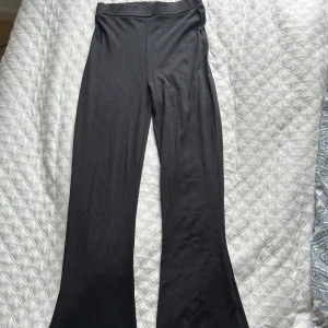 Svarta ribbade byxor - Snygga svarta ribbade byxor med en bekväm passform. Byxorna har en utsvängd stil och är perfekta för en avslappnad look. De är tillverkade i ett mjukt material som ger en skön känsla hela dagen.