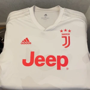 Juventus fotbollströja  - Säljer en vit Juventus fotbollströja från Adidas med röda detaljer. Storlek M