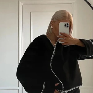 Svart kavaj med vita detaljer - Snygg svart kavaj med vita kontrastsömmar. Kavajen har en omlott-design och långa ärmar. Perfekt för en stilren look. Lite av det vita har ”gått upp” men tror det är lätt att fixa! Jag bara inte orkar göra det