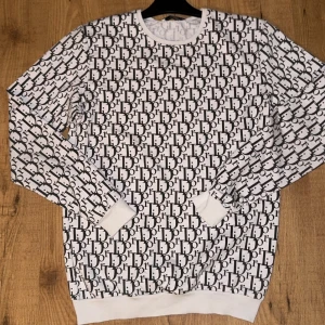 Vit och svart mönstrad tröja - Snygg vit tröja med svart mönster över hela ytan. Tröjan har långa ärmar och rund halsringning. Perfekt för en stilren look.