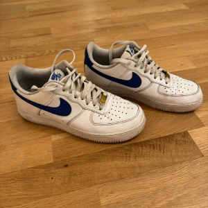 Nike Air Force i vitt och blått - Säljer ett par klassiska Nike Air Force sneakers i vitt med blå detaljer. Stl 41 