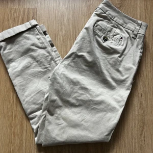 NYA- Beige chinos från Tommy Hilfiger - Snygga beige chinos från Tommy Hilfiger med klassisk design. Aldrig använd enbart testade. Storleken är 4 i USA men skulle säga att det är en 36 
