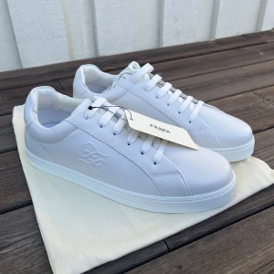 Helt nya Fendi sneakers (40 / unisex )  - Snygga vita sneakers från Fendi med stilren design och snörning. Skorna har en rund tå och är tillverkade i skinn, vilket ger en lyxig känsla. Perfekta för en minimalistisk look. Storlek 40, helt nya, aldrig använda. Nypris på dessa ligger på ca 9000 kr. OG dustbag ingår samt tags. 