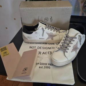 Vita golden goose - Snygga vita sneakers från Golden Goose med en grå stjärna på sidan och svarta detaljer vid hälen. Storlek 43. Insulan är 28 cm.
