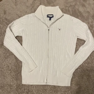 Vit stickad turtleneck med zip från GANT - Säljer en vit tröja från Gant då den inte längre passar mig, den är XL i juniorstorlek men den passade mig perfekt när jag hade S/XS så den är perfekt för något med den storleken!