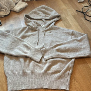 Beige hoodie från Gina young  - Säljer en mysig beige hoodie från Gina Tricot. Den har en klassisk design med huva och dragsko samt ribbade muddar vid ärmslut och nederkant. Perfekt för en avslappnad stil. Helt oanvänd utan lapp.