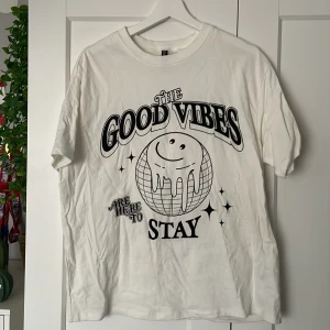 Vit t-shirt från H&M Divided - Säljer en vit t-shirt från H&M Divided med trycket 'The Good Vibes Are Here To Stay' och en glad jordglob. Perfekt för en avslappnad stil. 🌀