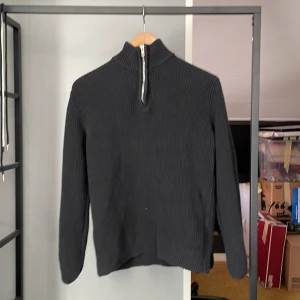 Svart stickad tröja med dragkedja  - Säljer en stilren svart stickad tröja från 157 med en praktisk dragkedja i halsen. Perfekt för kyligare dagar och enkel att matcha med olika outfits. Tröjan har långa ärmar och en ribbad struktur som ger en snygg passform.