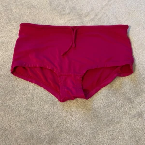 Rosa bikiniunderdel - Snygg rosa bikiniunderdel med hög midja och knytband framtill. Perfekt för en dag på stranden eller vid poolen.