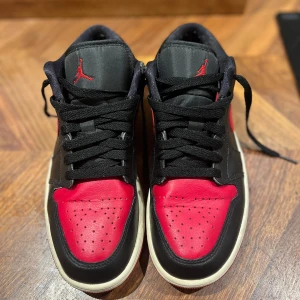 Jordan 1 low Röd svarta - Dessa skor är bara använde ett visst antal gånger och under sulan är som ny. Jag köpte dessa skor för 1000kr nya.  