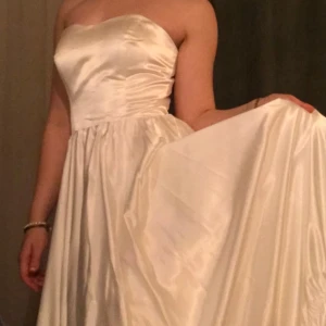 Vacker Bröllopsklänning  - Oanvänd elegant axelbandslös brudklänning i satin. Klänningen har en vacker glans och en smickrande passform. Den har även en inbyggd BH och korsettknytning i ryggen. Skulle uppskatta att den passar storlekarna 36-42. 