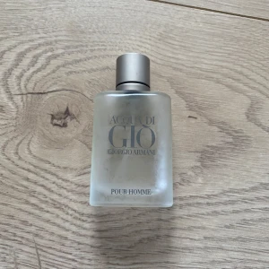 Acqua di Giò Pour Homme från Giorgio Armani - 25% kvar av perfymen) Säljer en klassisk herrparfym, Acqua di Giò Pour Homme från Giorgio Armani. Flaskan är frostad med en stilren design och har en grå kork. Perfekt för den som söker en fräsch och tidlös doft.
