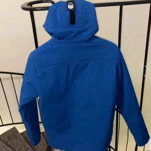 Blå jacka från sali Racing  - Säljer en snygg blå jacka från sali Racing. Jackan har en praktisk huva och dragkedja framtill. Perfekt för kyligare dagar med sin stilrena design och funktionella fickor.