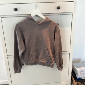 Brun hoodie - Säljer en brun hoodie med känguruficka framtill. Tröjan har långa ärmar och en bekväm huva. Perfekt för en avslappnad stil.