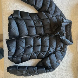 Svart dunjacka från Colmar - Säljer en stilren svart dunjacka från Colmar. Jackan har en quiltad design med dragkedja framtill och en hög krage för extra värme. Perfekt för kyliga dagar och ger en snygg look. 🖤osäker på exakta storlek men vill säga S. Knappt använd och nypris är ca 3990kr✨