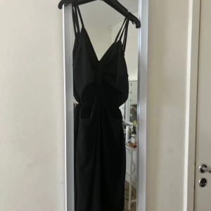 Svart klänning med rosett - Elegant svart klänning med smala axelband och en vacker rosett. Aldrig använd! 